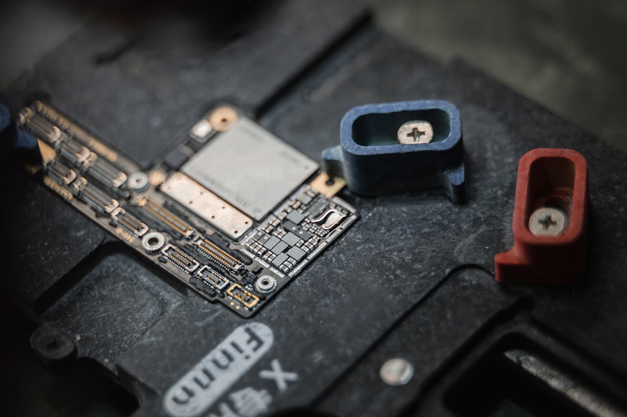 services-03 Detailed view of a circuit board with components and colored screws on a dark surface.